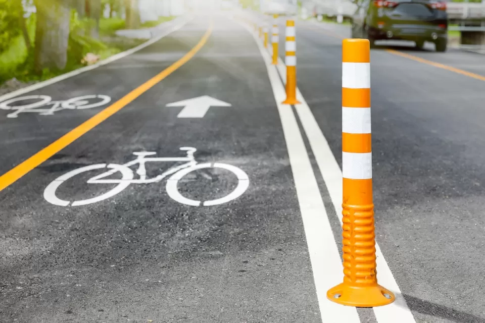 Bike lane delineated with white paint and orange bollards.
